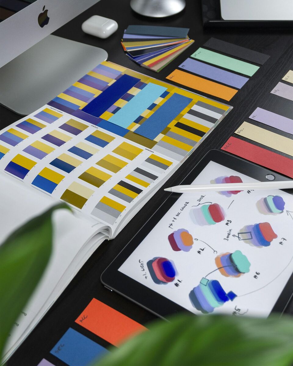 Close-up de mão feminina segurando fichas com amostras de papel colorido e tecido para definir paleta de cores de branding